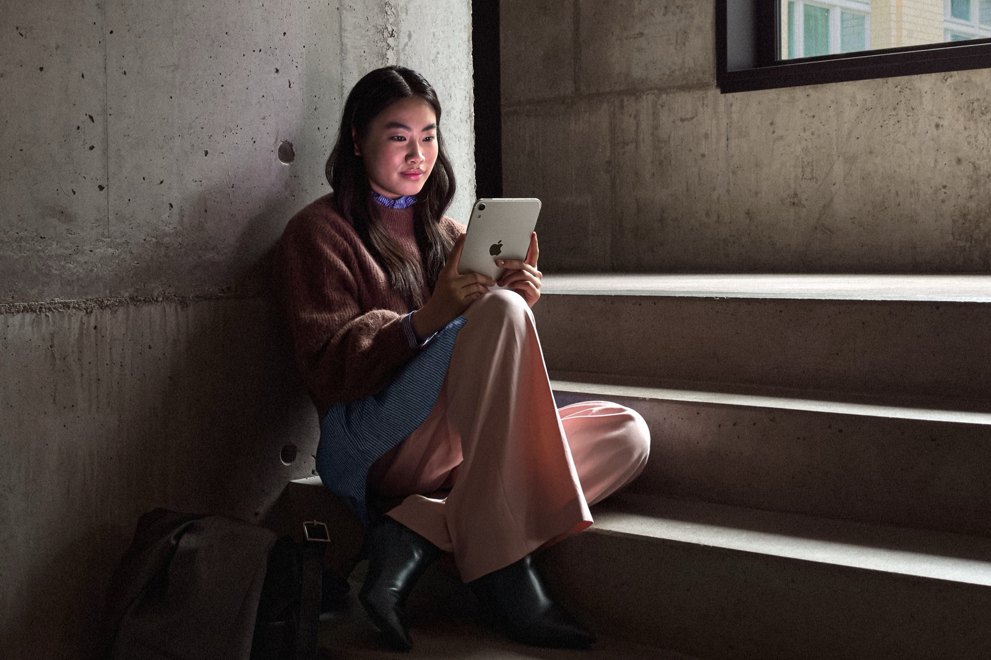 ผู้หญิงนั่งบนบันไดถือ iPad mini มองไปที่หน้าจอ